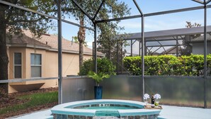 A swimming pool with a hot tub, surrounded by a glass enclosure, and a house in the background. - Luxury relaxing stay. A brand new remodel villa near Disney and Legoland  (Haines City)