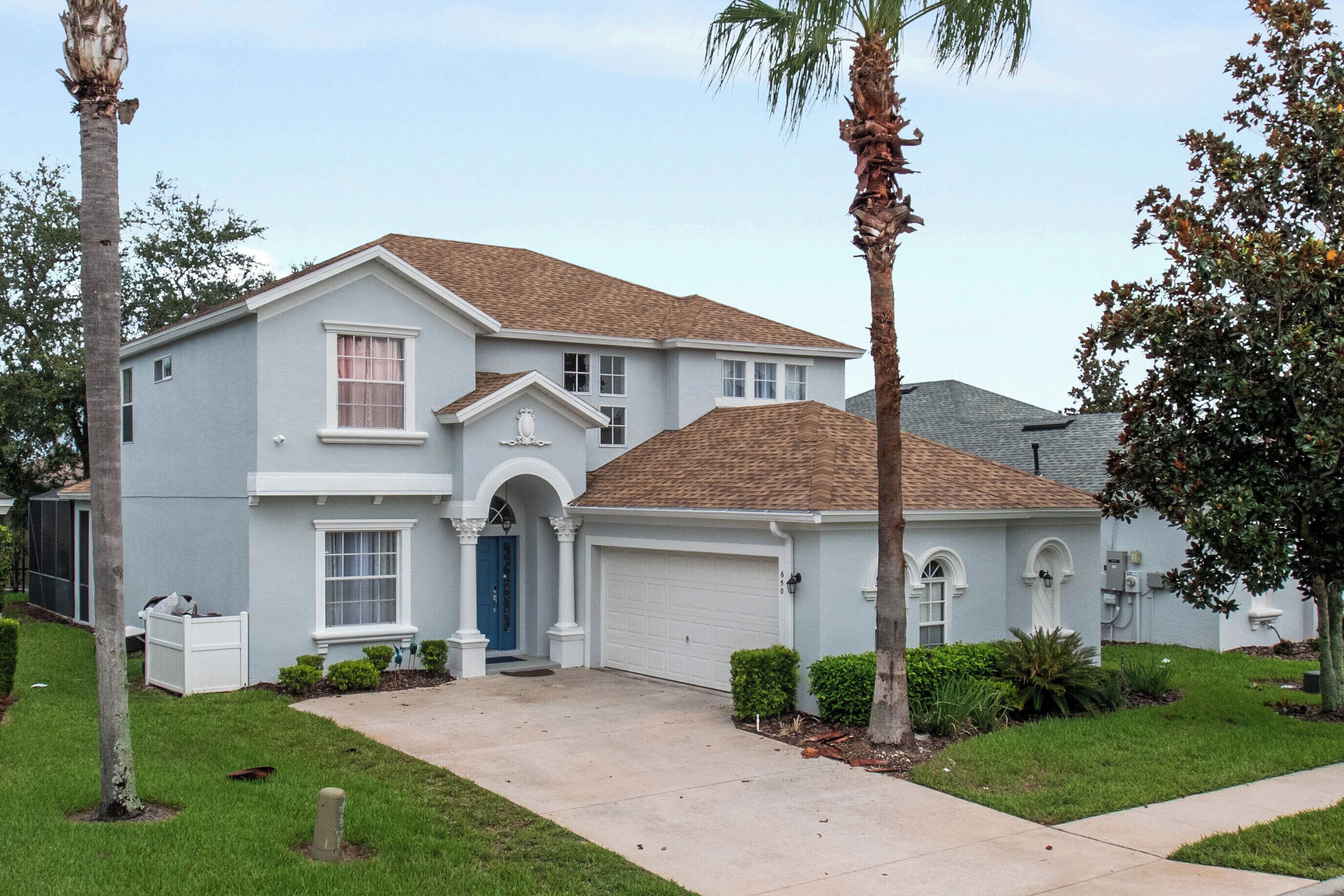A two-story house with a front garage, a small porch, and a well-maintained lawn.