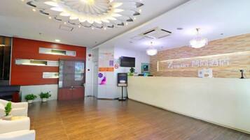 A hotel reception area with a modern design, including a reception desk, seating area, and a decorative ceiling light fixture.