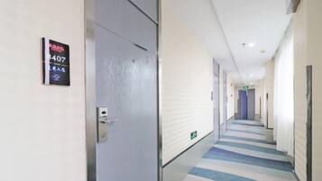 A hotel corridor with a striped carpet, a door with a sign, and a long hallway.