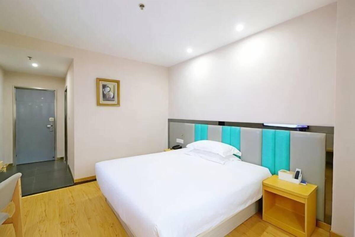 Quarto de hotel com uma cama, mesa de cabeceira e uma cadeira.