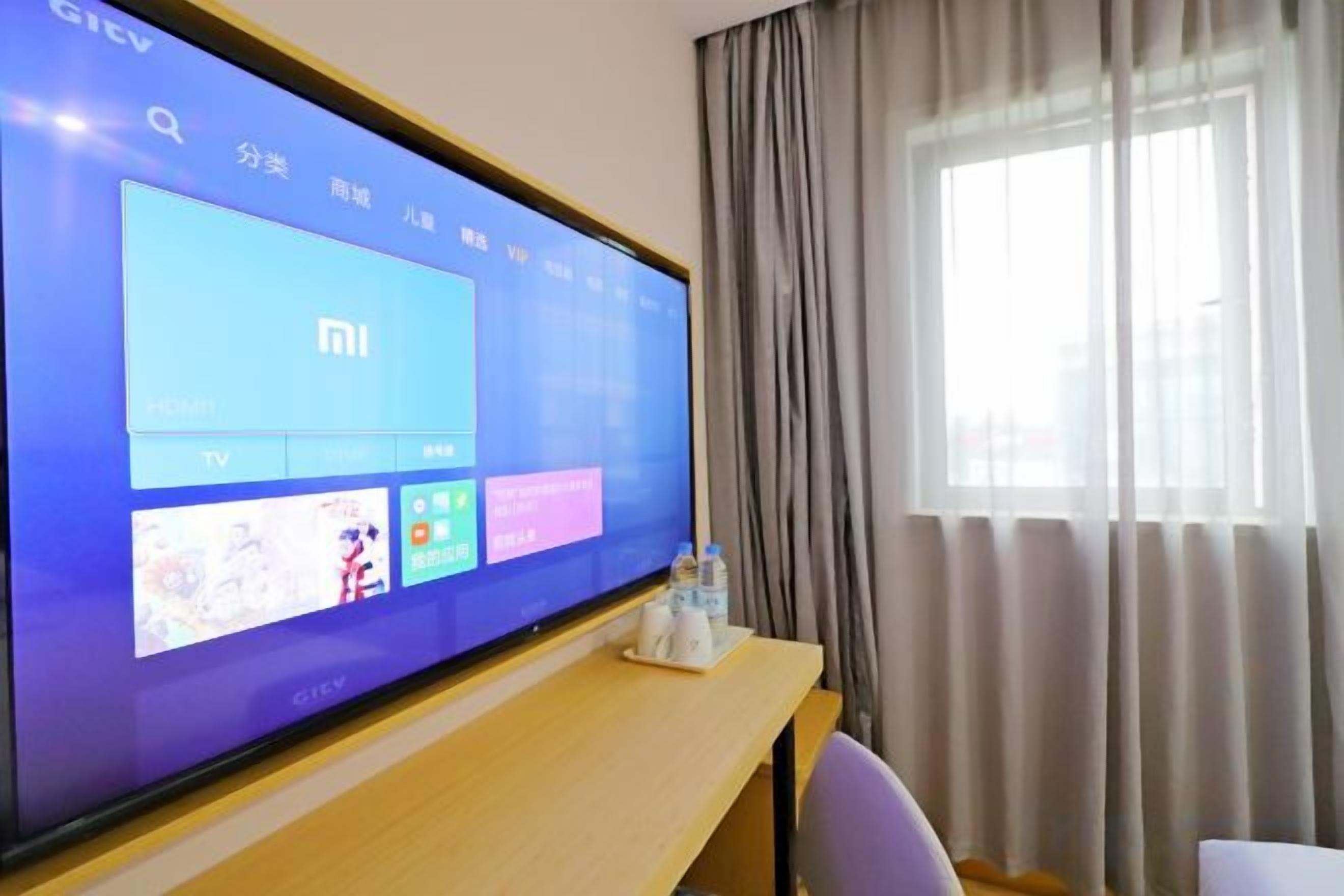 Ein Fernsehbildschirm zeigt eine Unterhaltungs-Benutzeroberfläche mit einer Suchleiste und verschiedenen App-Symbolen.