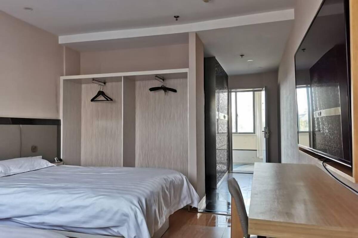 Quarto de hotel moderno com cama, escrivaninha e um espelho grande.