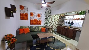 Sala de estar com sofá, mesa de centro e área de jantar com toalha quadriculada.