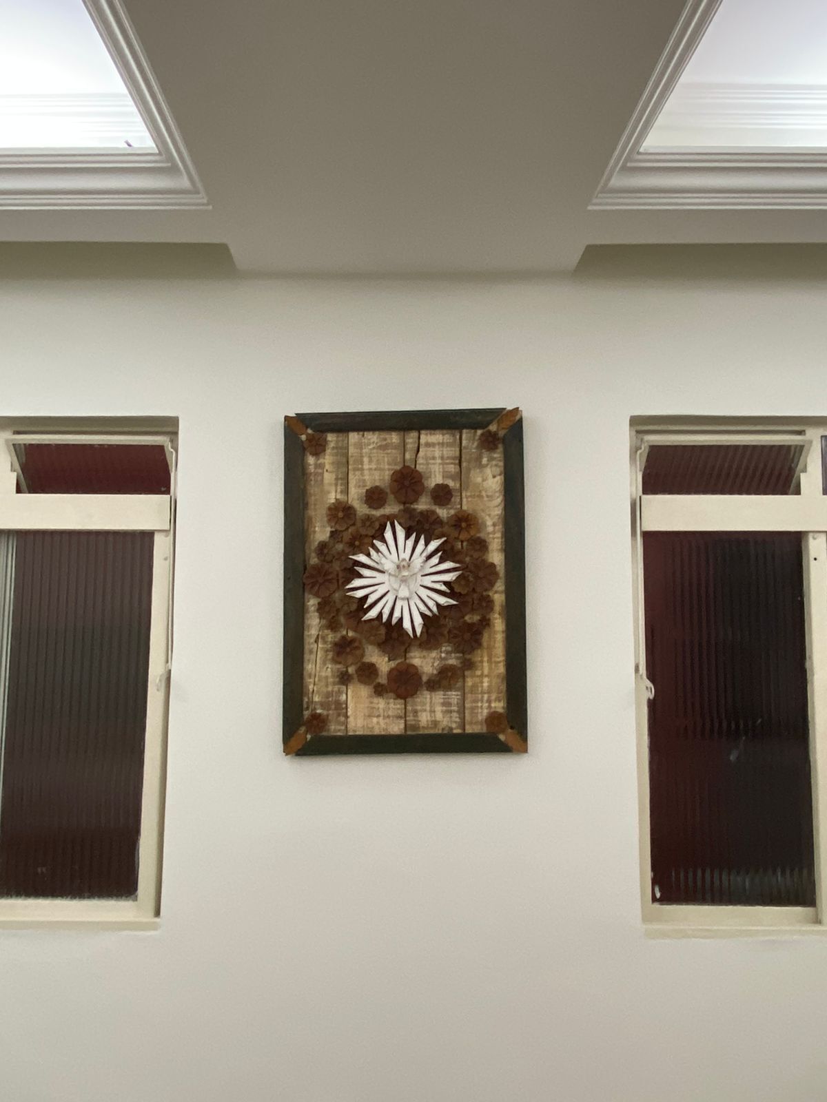 Una habitación con tragaluz en el techo, una obra de arte enmarcada en la pared y dos ventanas con persianas.