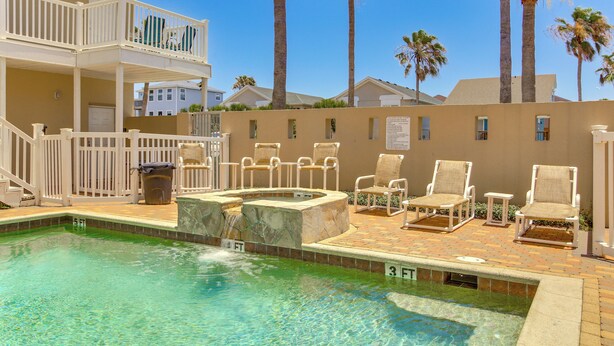 A pool area with lounge chairs, a hot tub, and a two-story building with balconies. - South Padre Island: Pool Access, 1 Block to Beach! (South Padre Island)