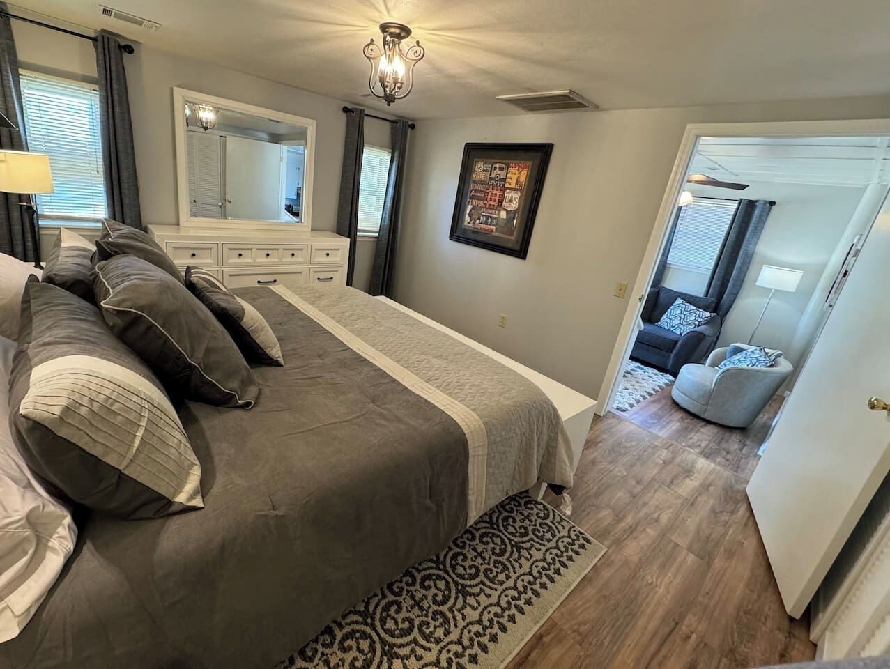 Un dormitorio con una cama grande, un aparador, un espejo y una puerta que da a otra habitación.