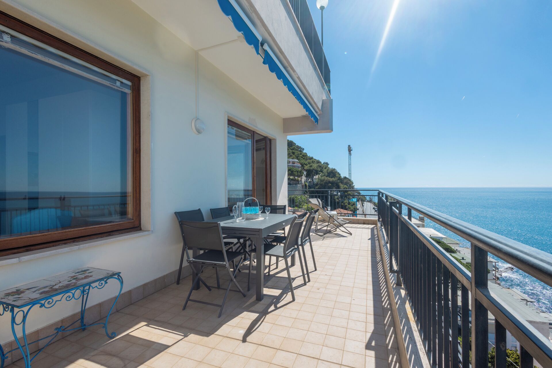 Un balcone con tavolo e sedie, affacciato su una vista costiera.