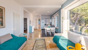 A modern living room with a sofa, a glass coffee table, and a view of a balcony. - Sky & Sea Apartment by Wonderful Italy (Ospedaletti)