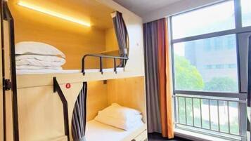 Quarto com beliche, janela e cortinas.