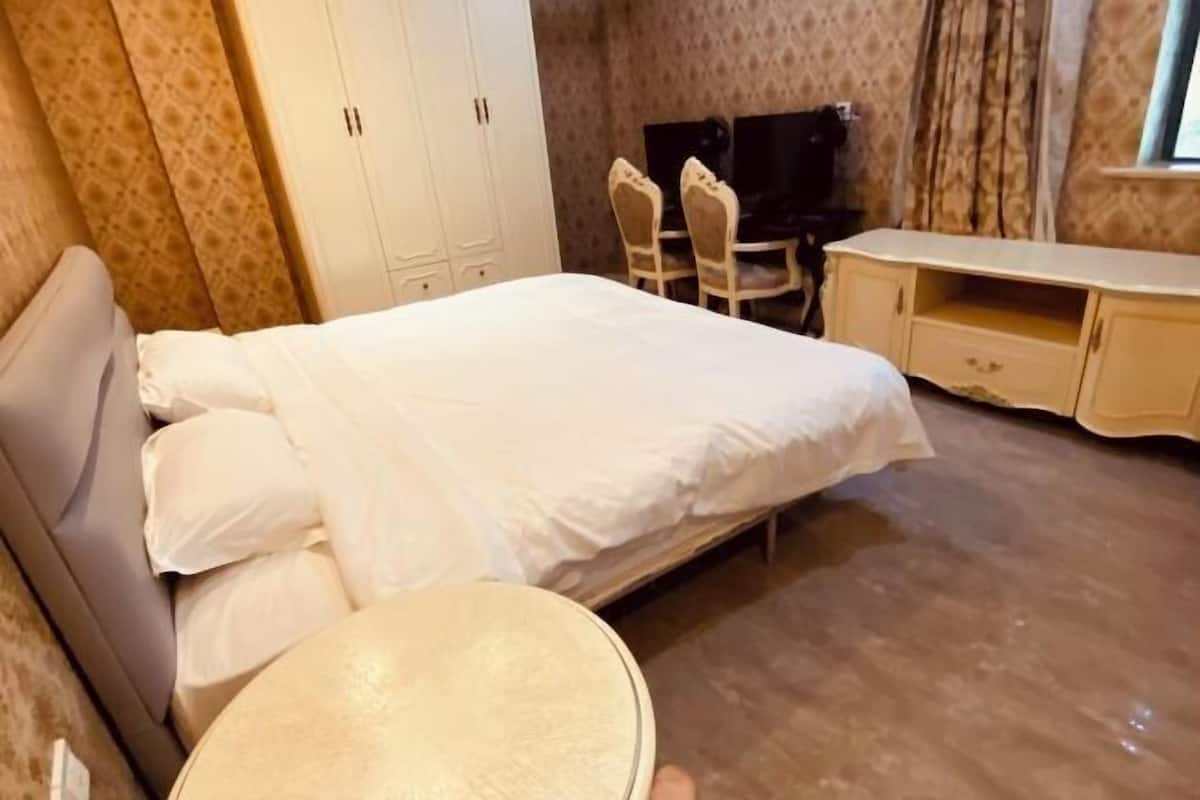 Ein Hotelzimmer mit einem Bett, einem kleinen runden Tisch, einem Fernseher und einem Schreibtisch mit Stühlen.