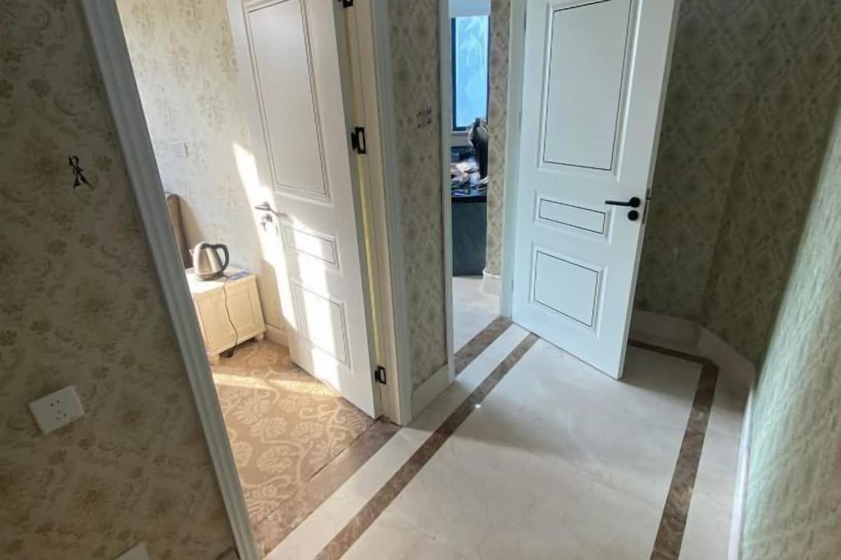 Ein Korridor mit gemustertem Wandpapier, einer weißen Tür und einem gefliesten Boden.