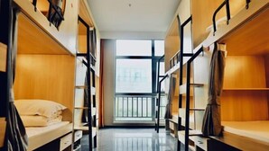 Une chambre de dortoir avec des lits superposés, une fenêtre donnant sur un beau paysage et un plancher en bois.