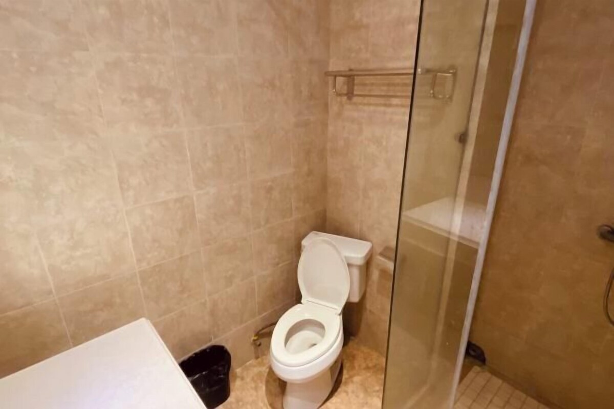 Een kleine badkamer met toilet, een douchecabine van glas en een prullenbak.