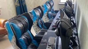 Une rangée de fauteuils de jeu, avec un ensemble informatique comprenant un clavier, une souris et un casque.