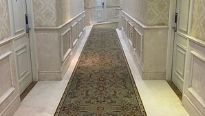 Un couloir avec un tapis à motifs, des murs blancs et des portes de part et d’autre.
