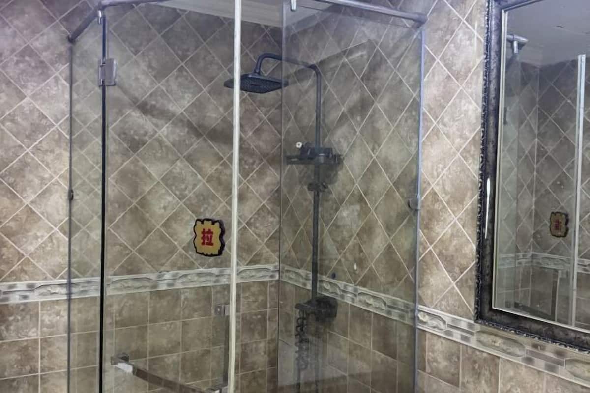 Eine Duschkabine mit Glaswänden, einer gefliesten Wand und einer dekorativen Plakette.