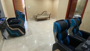 Une pièce comprenant deux fauteuils de jeu, un canapé vintage et un petit bureau avec un clavier.