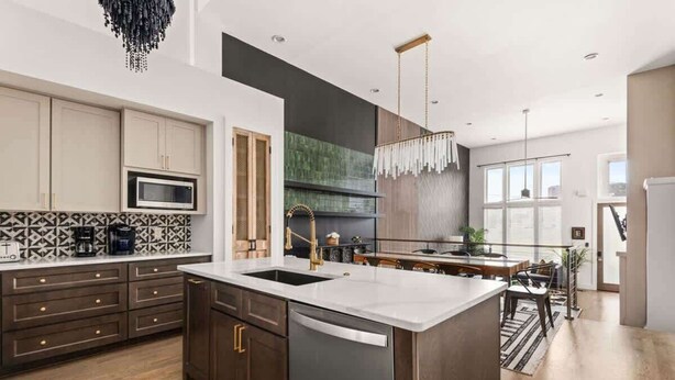 A modern kitchen with a central island, wooden cabinets, a microwave, and a hanging light fixture. - Centennial Quarters: Holiday House near Vandy! (Nashville)