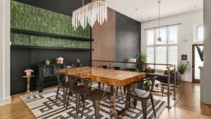 A modern dining area with a wooden table, chairs, and a hanging light fixture. - Centennial Quarters: Holiday House near Vandy! (Nashville)