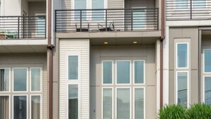 A modern multi-story residential building with a balcony, large windows, and a stone facade. - Centennial Quarters: Holiday House near Vandy! (Nashville)