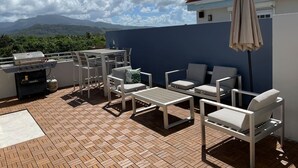 An outdoor patio with a grill, seating area, and a view of mountains. - Luxury Beach Penthouse Luquillo (Luquillo)