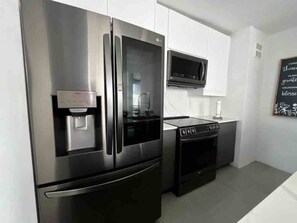 Een keuken met roestvrijstalen apparatuur, waaronder een koelkast, oven en magnetron.