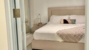 A bedroom with a bed, bedside table, lamp, and a sliding door. - Luxury Beach Penthouse Luquillo (Luquillo)