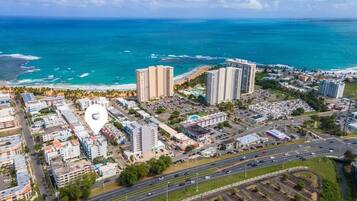 An aerial view of a coastal city with high-rise buildings, a beach, and a road network.