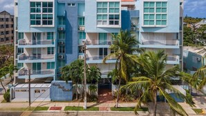 A multi-story hotel with balconies, palm trees, and a clear sky. - Luxury Beach Penthouse Luquillo (Luquillo)