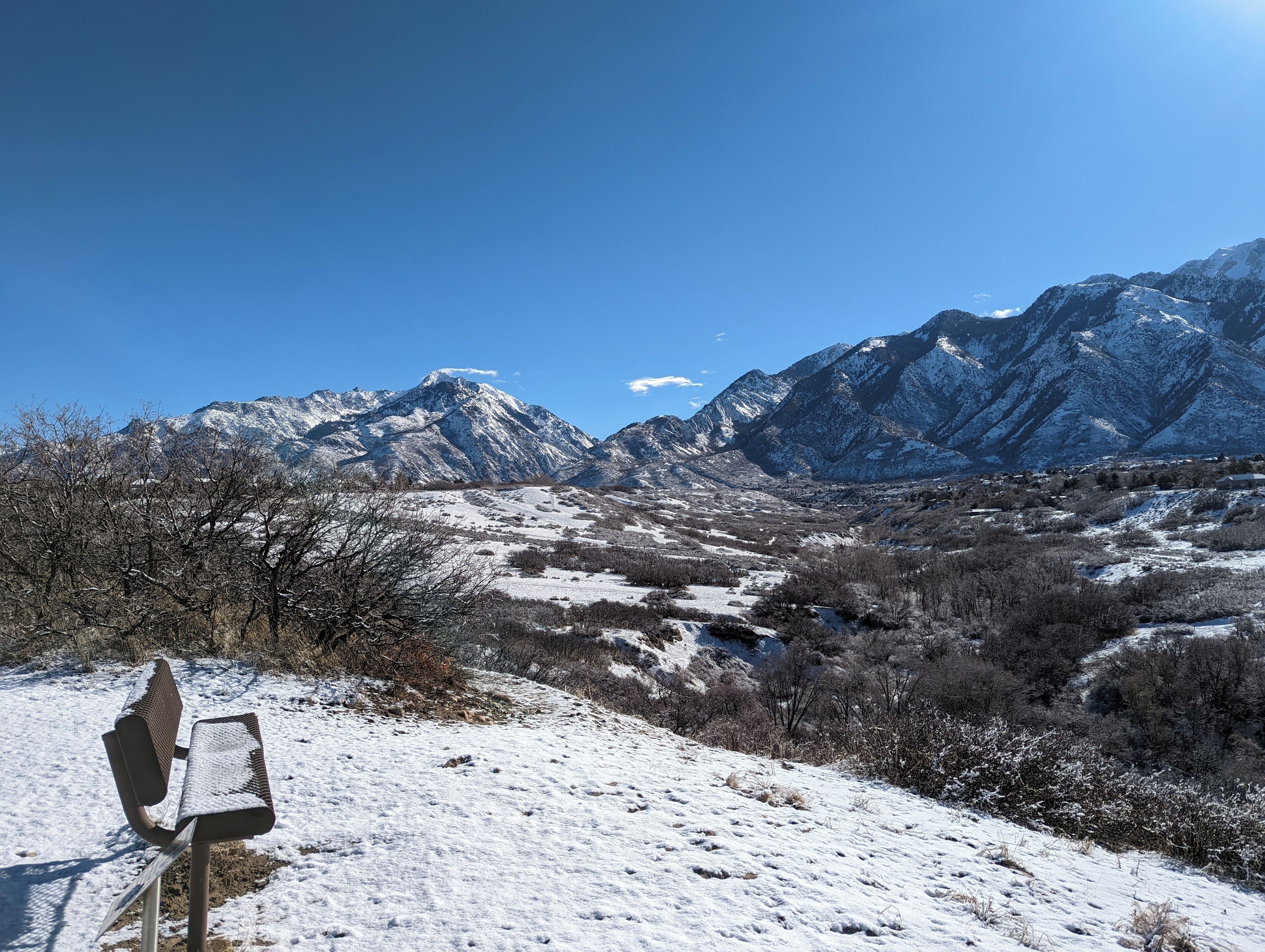 A bench in a snowy landscape with mountains in the background.