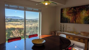 A dining area with a large table, chairs, a bowl, a cabinet with decorative items, and a painting of a landscape. - Nature's Playground for All Seasons. Near World Class Ski Resorts & Golf Courses (Sandy)