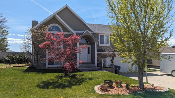 A residential house with a pitched roof, a front porch, and a small front yard with a tree and potted plants. - Nature's Playground for All Seasons. Near World Class Ski Resorts & Golf Courses (Sandy)