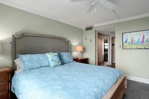 A bedroom with a large bed, a nightstand, a lamp, and a painting on the wall. - Coquina A104 Ground floor walk out unit. Direct Ocean View! (Saint Augustine Beach Florida)