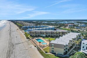 A coastal hotel with multiple buildings, a swimming pool, and a beach view. - Coquina A104 Ground floor walk out unit. Direct Ocean View! (Saint Augustine Beach Florida)