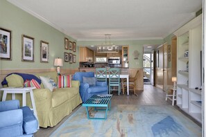 A living room with a sofa, chairs, a coffee table, and a kitchen in the background. - Coquina A104 Ground floor walk out unit. Direct Ocean View! (Saint Augustine Beach Florida)