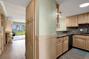 Una cocina con armarios de madera, encimera de granito y vistas al exterior.