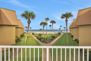 Un resort con varias construcciones, palmeras y vista al mar.