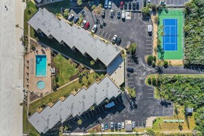 An aerial view of a hotel with a swimming pool, tennis court, and parking lot. - Ocean front condo w/ gorgeous direct beach view & pool/tennis access! (St. Augustine)