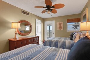 Un dormitorio con dos camas, un ventilador de techo, un aparador y un espejo.
