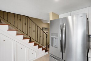 Cocina con un refrigerador de acero inoxidable y una escalera de madera con barandillas negras.