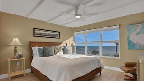 Ein Schlafzimmer mit einem großen Bett, einem Deckenventilator, einem Fenster mit Aussicht und einem Gemälde an der Wand.
