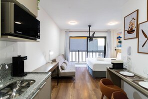 A compact hotel room with a kitchenette, a sofa, a bed, and a small dining area. - My One Bela Vista (São Paulo)