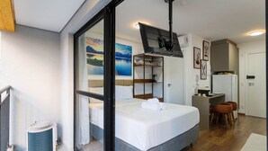 A hotel room with a bed, a desk, a chair, a TV, and a window with a view of a landscape. - My One Bela Vista  (São Paulo)