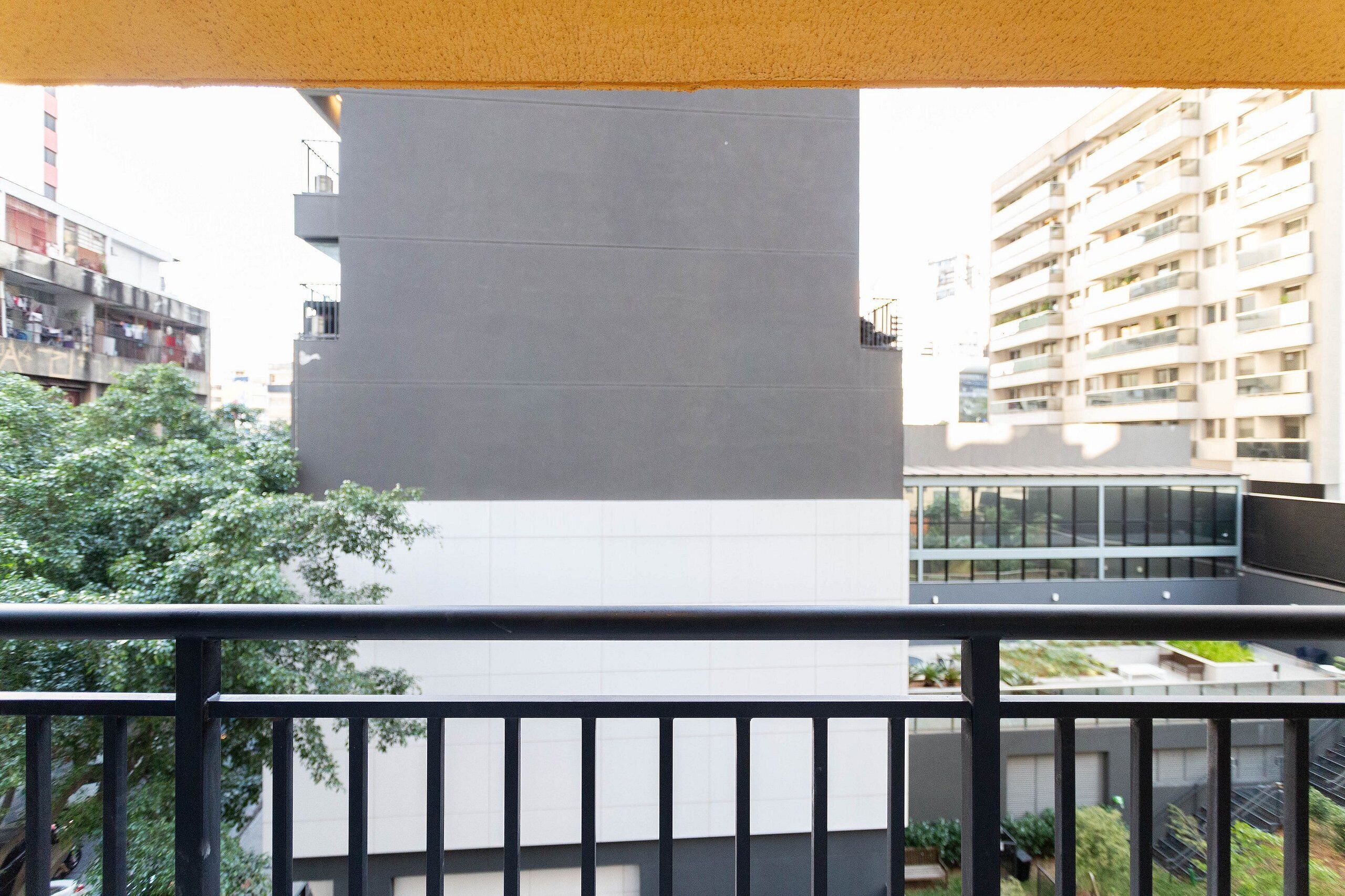 Un balcón con vista a un edificio moderno de techo plano y un ventanal grande.