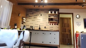 A spacious kitchen with wooden beams, a white countertop, and a large window. - Red Barn Lindo Celeiro em Urubici - SC (Urubici)