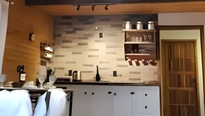 A modern kitchen with wooden beams, a central island, and built-in appliances. - Red Barn Lindo Celeiro em Urubici - SC (Urubici)