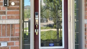 A red door with a glass panel and a keypad lock. - Executive End Unit Townhome (Milton)