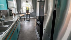 A kitchen with teal cabinets, stainless steel appliances, a dining area with a table and chairs, and a hanging light fixture. - Robin's Bluff- Classic 3-bedroom in beautiful Whitefish Bay, convenient location (Whitefish Bay)