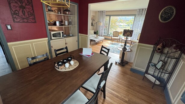 A dining area with a wooden table, chairs, a chandelier, and a view of the outdoors. - Robin's Bluff- Classic 3-bedroom in beautiful Whitefish Bay, convenient location (Whitefish Bay)